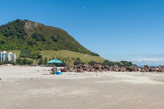 Main Beach and umbrella over picnic items  and Mount Maunganui background.