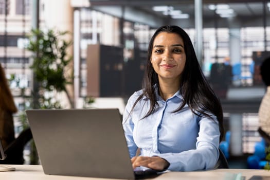 Account executive multitasking at her desk working on business goals. Female employee uses her computer for data management and project strategy, infographics analytics numbers.
