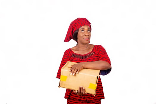 beautiful african adult woman wearing red loincloth standing,Looking on the side holding a cardboard box smiling isolated on a white background
