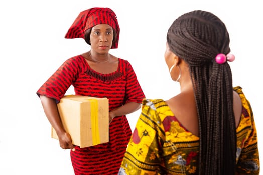 beautiful adult businesswoman smiling while receiving a parcel box from a woman dressed in red loincloth in her office
