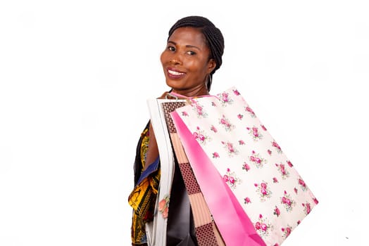 Portrait of happy beautiful african adult woman holding paper bags in hand and smiling while standing isolated on white background