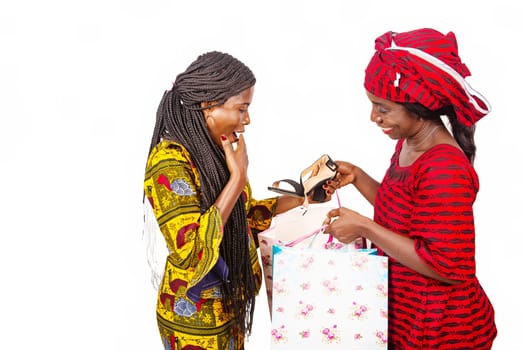 beautiful surprised african adult customer receiving a pair of shoe with delivery service inside a woman wearing a red loincloth using bags