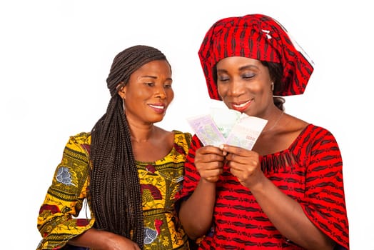 two beautiful businesswomen standing in traditional dress on white background looking at bank notes smiling.