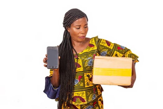 beautiful african woman standing in traditional outfit on white background showing cell phone wearing a cardboard.