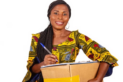 beautiful african woman standing in traditional outfit on white background smiling ready to sign a document after receiving a package.
