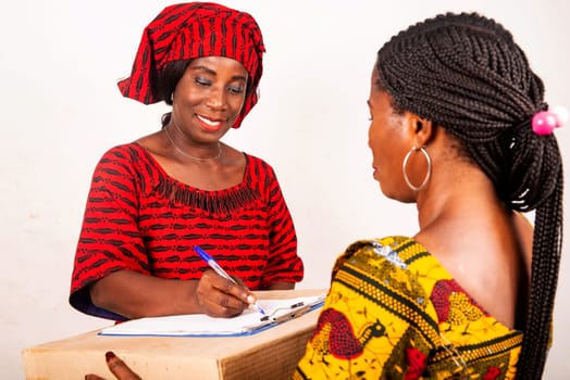 beautiful african woman standing in traditional dress on white background smiling signing a document after receiving an online package.