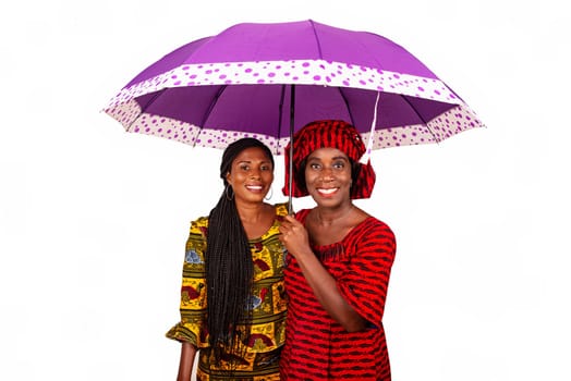 two beautiful business women standing together under a purple umbrella while being smiling