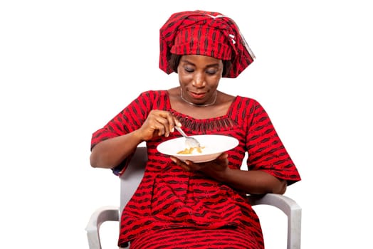 beautiful adult woman wearing a suit of loincloth while sitting on a chair eating an African meal while being smiling