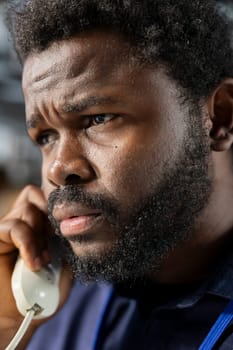 African american employee using the office landline phone to stay connected with the other business departments, receiving a call to discuss about daily administrative tasks. Close up.