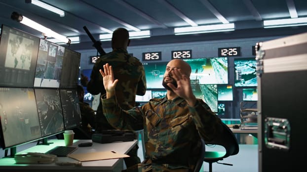 Military agent using augmented reality tech in control room, analyzing aerial reconnaissance data. Intelligence corps expert controlling drones attacking strategic targets using AR hologram, camera B