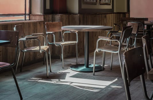 Royal Tunbridge Wells, UK - Apr 29, 2025 - Table at a restaurant with sunlight coming in through the Large windows, casting beautiful light and shadow patterns on the dining table and chairs at empty restaurant. use it as your Wallpaper, Poster and Space for text, Selective focus.