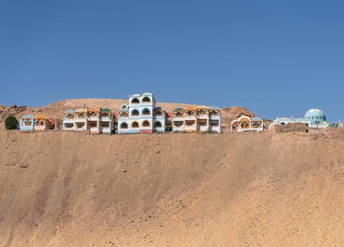 Colorful building of Nubian holiday resort on top of sandy hill in Aswan, Egypt by the river Nile