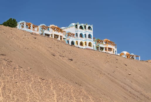 Colorful building of Nubian holiday resort on top of sandy hill in Aswan, Egypt by the river Nile