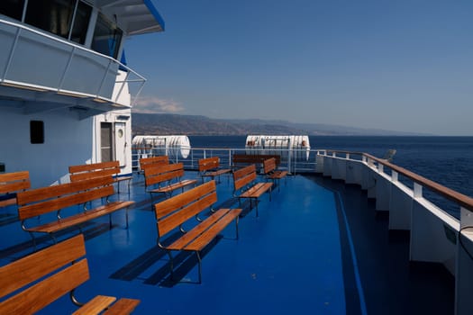 Sicily, Italy - 27.07.2024: Scenic ferry deck with empty benches overlooking the sea and distant horizon.