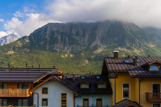 Passo Tonale, Italy - 10.08.2024: Scenic mountain view with charming village houses amidst lush greenery.