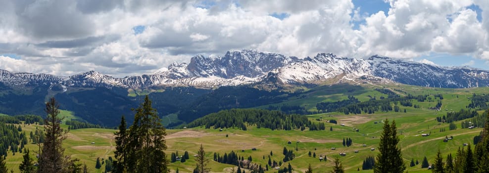 Majestic alpine landscape with snow capped mountains and verdant valleys near Valley of Funes at Dolomites, Italy.