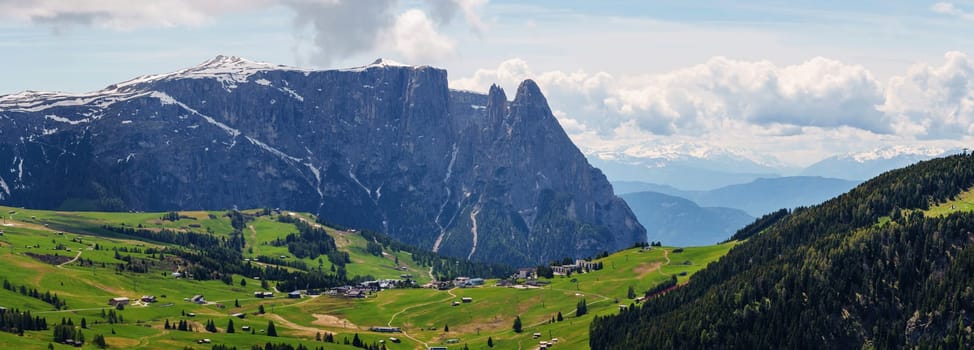 Majestic mountain landscape view of verdant valleys and snow capped peaks in early spring near Valley of Funes at Dolomites, Italy.