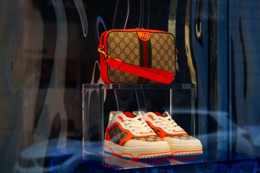 Milan, Italy - 24.04.2024: Luxury fashion Gucci display with designer sneaker and handbag in boutique window.