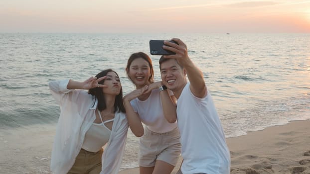 Happy friends smiling and posing taking selfie from smartphone and having fun together on beach in holiday vacation time at sunset, Young Asian group woman and man in summer travel outdoor