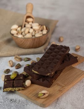 Gourmet chocolate mixed with crunchy kadaif pistachio pieces is beautifully presented on a wooden board, making a perfect treat in Dubai's culinary scene.