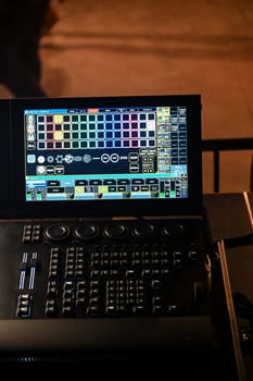 A detailed view of a lighting control panel featuring multiple digital displays and buttons, actively being used during a rehearsal at a theater venue.