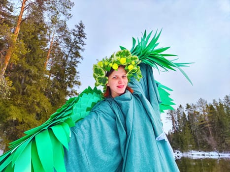 A girl in a vibrant green dress stands by a serene lake, embracing the essence of spring with her joyful pose and nature-themed attire.