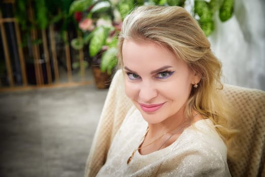 A middle-aged woman captures a selfie while modeling in her stylish indoor living space, radiating confidence.