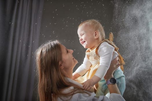 A mother and daughter joyfully engage in a flour-filled moment, creating memories in a cozy kitchen setting.