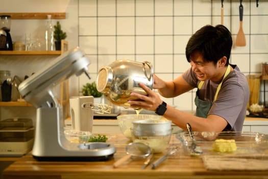 Smiling man pouring creamy mixture from bowl during the preparation of compound butter.