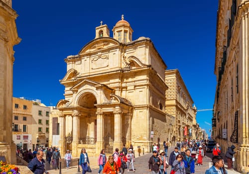 Valletta, Malta - April 2, 2025: Tourists walking near The Church of St Catherine of Alexandria, Knisja Santa Katerina tal-Italja