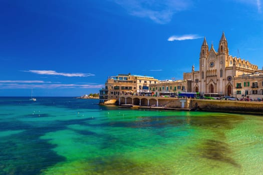 Picturesque view of the Knisja tal-Karmnu and turquise-green water in St. Julian's Bay in Sliema, Malta.