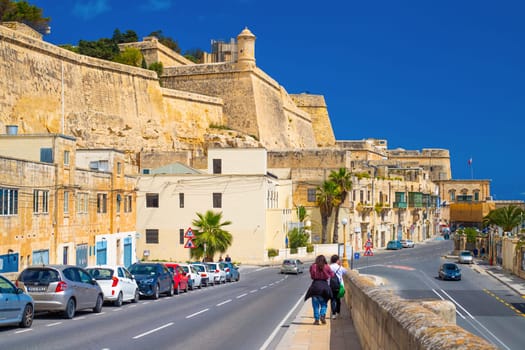 Valletta, Malta - April 2, 2025: A couple of tourists walk along the ramparts of Valletta towards the Upper Barrakka.