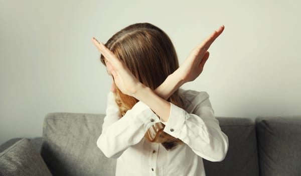 Close-up upset young woman shows stop, no or enough sign with palm of hand, refusal gesture, domestic violence