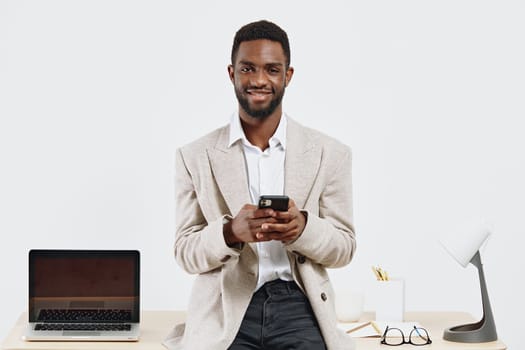 Cheerful man working in modern office environment, holding mobile device with a bright background. Tech-savvy professional enjoying digital communication and productivity in a stylish workspace. Concept: modern professional.