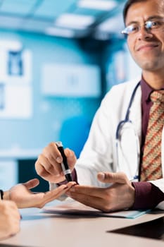 Indian physician prepares insulin pen for patient injection during a clinic visit, treating diabetes. Medic discusses disease diagnostic reports in a professional healthcare cabinet. Close up.