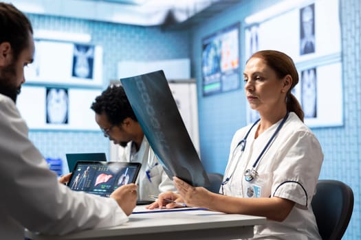 Medical experts collaborating on x ray analysis in a private clinic, collective work ensuring precise diagnostics and effective treatment plans. Highlighting professional healthcare teamwork.