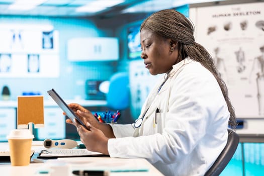 Black physician providing checkup examination on insurance with patient, employing technology for diagnostic tools in clinic. Man asking medic about wellness advice, recovery plan.