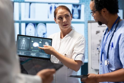 Medical team examining x ray scan results to discuss patient care options. Group of licensed cardiologists analyzing cardiac issues on a ecg radiography, effective treatment in a clinic.