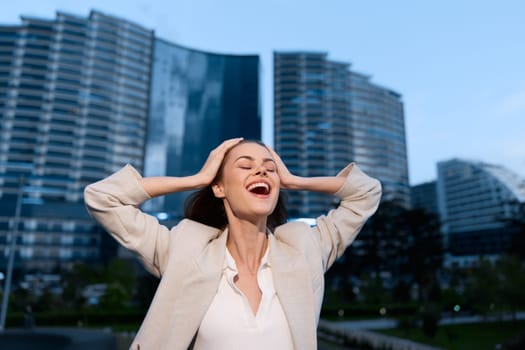Young woman with light skin expressing relief and joy near modern skyscrapers, symbolizing recovery from financial crisis and economic stress in business context.