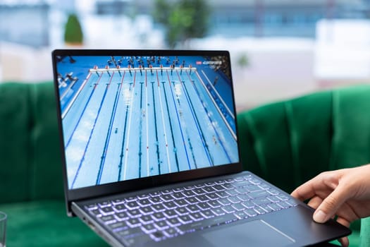 Bucharest, Romania - July 30th 2024 - Young adult watching the Olympic Games competition, supporting the national champion via live stream online. Male spectator in his personal office.