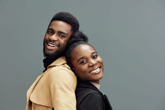 Happy African couple expressing love and joy through their smiles, dressed in trendy attires, set against a simple gray backdrop, perfect for diversity and relationships concepts
