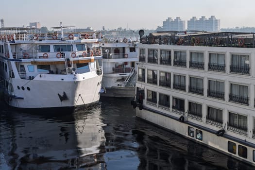 Many cruise ships docked side by side seen from deck of Nile cruise boat in congested Edfu harbor Egypt