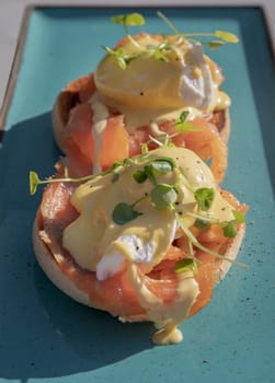 Eggs Royale made with english muffin, oak smoked salmon, a brace of poached hen's eggs & hollandaise sauce and watercress served on blue ceramic tray. use it as your Wallpaper, Poster and Space for text, Selective focus.