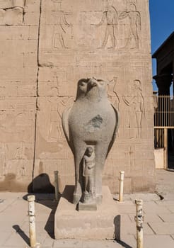Detail of the carved statue of Horus outside the Pylon at the entrance in Edfu protecting a child or young pharoah