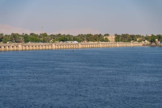 Old Esna dam and lock across the Nile River with sandy hills of Sahara desert behind