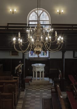 Royal Tunbridge Wells, UK - Apr 29, 2025 - Stunning view of Chandelier hanging from the ceiling over The white octagonal baptismal font inside of The Church of King Charles the Martyr, is a Church of England parish church in Royal Tunbridge Wells, Kent, England. use it as your Wallpaper, Poster and Copy space, Selective focus.