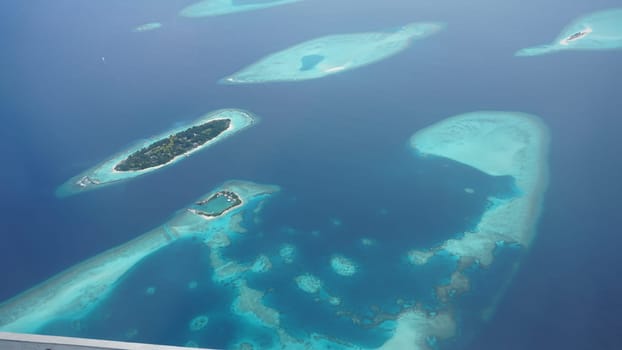 Aerial view of the maldives archipelago, showcasing the stunning contrast between the turquoise waters and the lush green vegetation of the islands