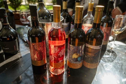 Odessa, Ukraine - April 05, 2025: Bottles of wine on a black table outdoors in a hotel. wine tasting at a city fair in soft natural light