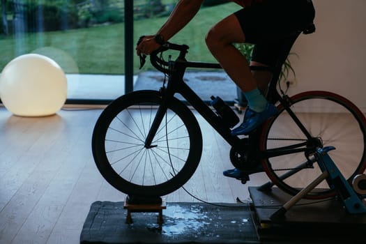 A triathlete riding a triathlon bike on a machine simulation in a modern living room. Training during pandemic conditions