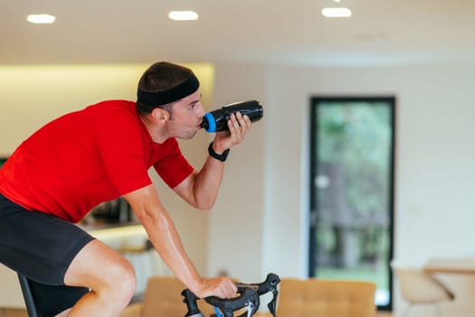 A triathlete riding a triathlon bike on a machine simulation in a modern living room. Training during pandemic conditions